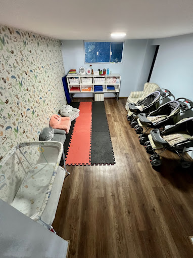 Sala de primeira infância do CEMEL com berços, carrinhos e área de circulação
