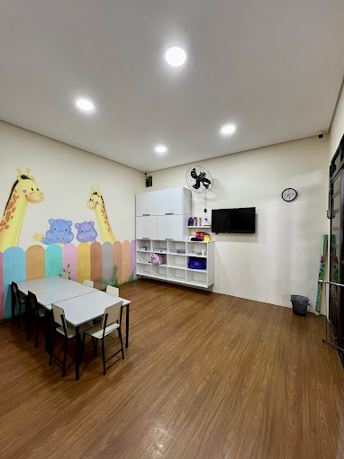 Ambiente infantil do CEMEL com pequenas mesas, brinquedos e parede ilustrada